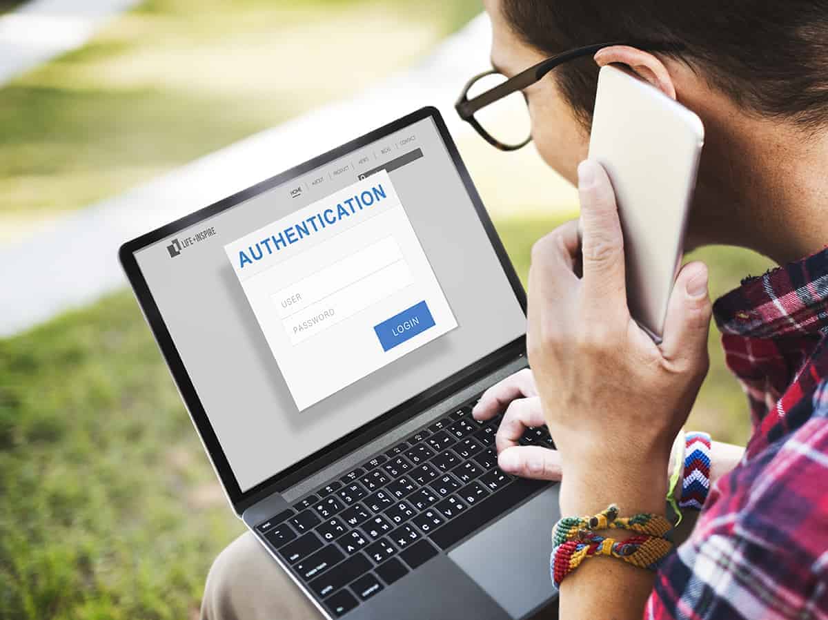 a man using a phone and laptop with authentication prompt on the screen